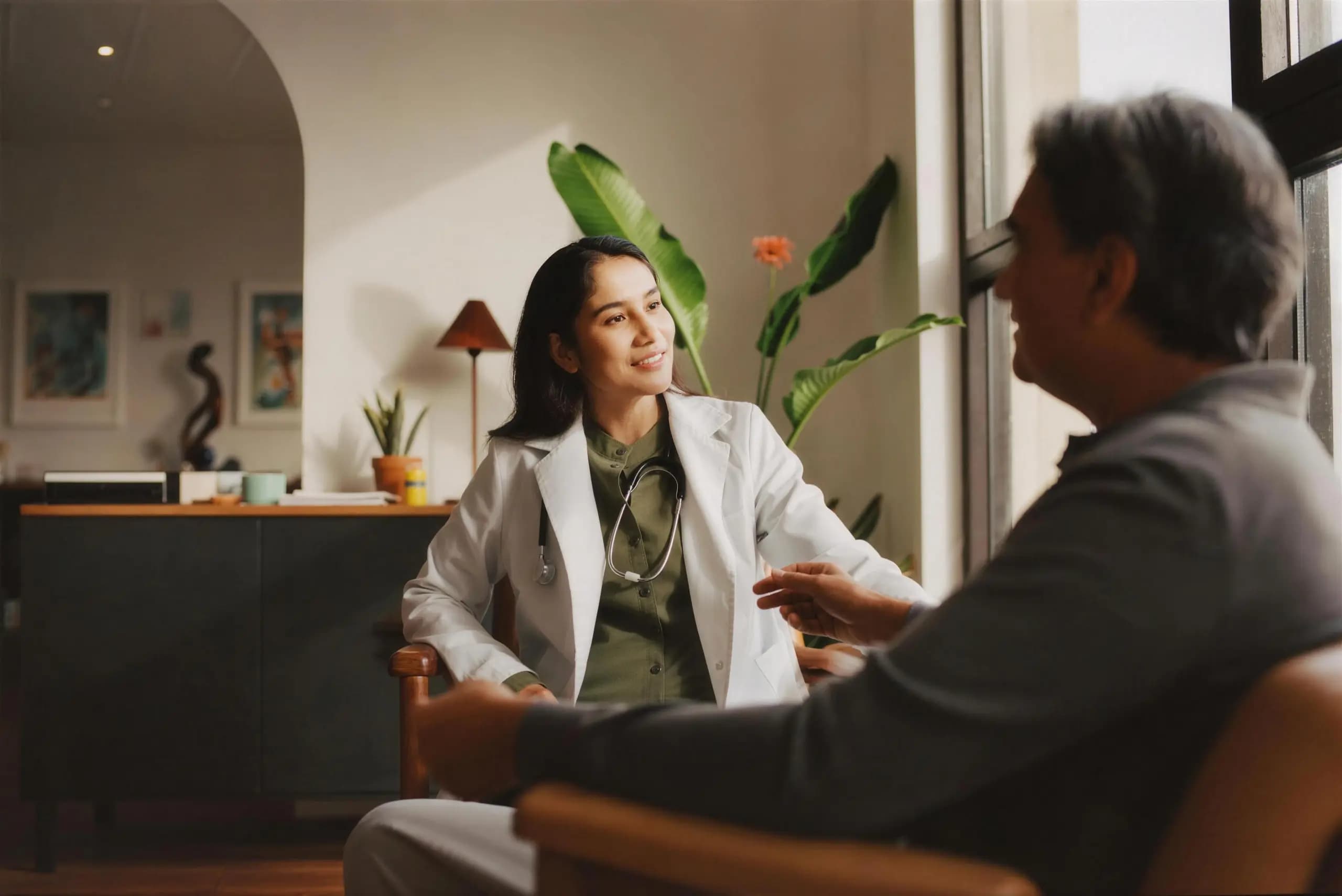 A doctor in a warm, sunlit consultation room, talking with a patient